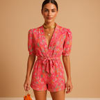Women’s short summer jumpsuit with vibrant print and waist belt, available in pink and purple, perfect for warm days and summer outings.